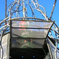 A DJ in the glass cab of a tall welded metal art structure