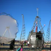 Large welded metal art vehicle with two white inflatable sails standing in the desert