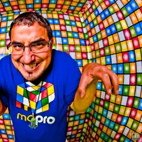Fisheye photo of MontsDe in a blue Mo'Pro cube-logo shirt inside a room tiled with colorful squares