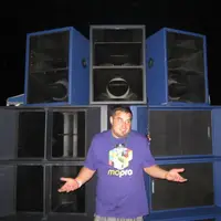 Person in a Mo'Pro shirt standing in front of a wall of large blue speaker cabinets at night