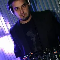 DJ in headphones behind a mixer lit in purple