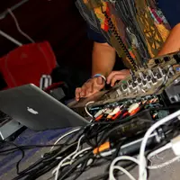 DJ in a red cap and headphones mixing with a laptop beside the decks
