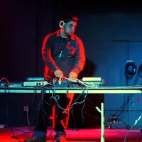 DJ mixing at a table on a stage under deep red light