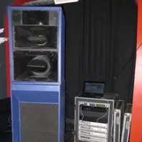 Tall blue speaker stack next to an amplifier rack case and a monitor backstage